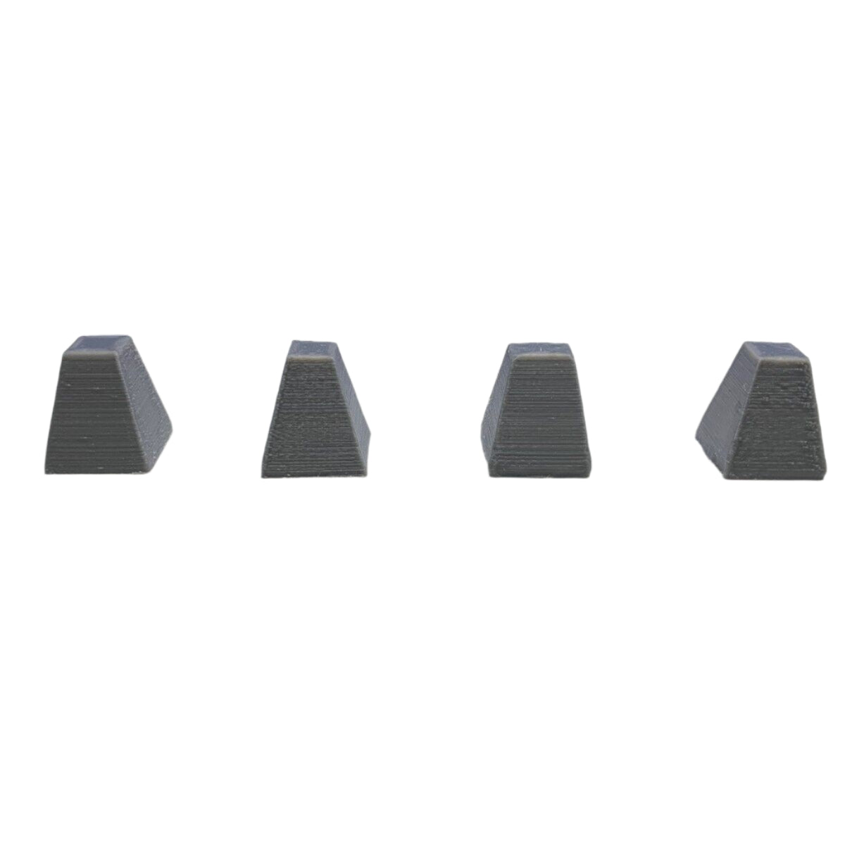 Four grey 3D printed Dragon’s Teeth anti-tank barriers aligned in a straight row for model railways, wargaming, and dioramas