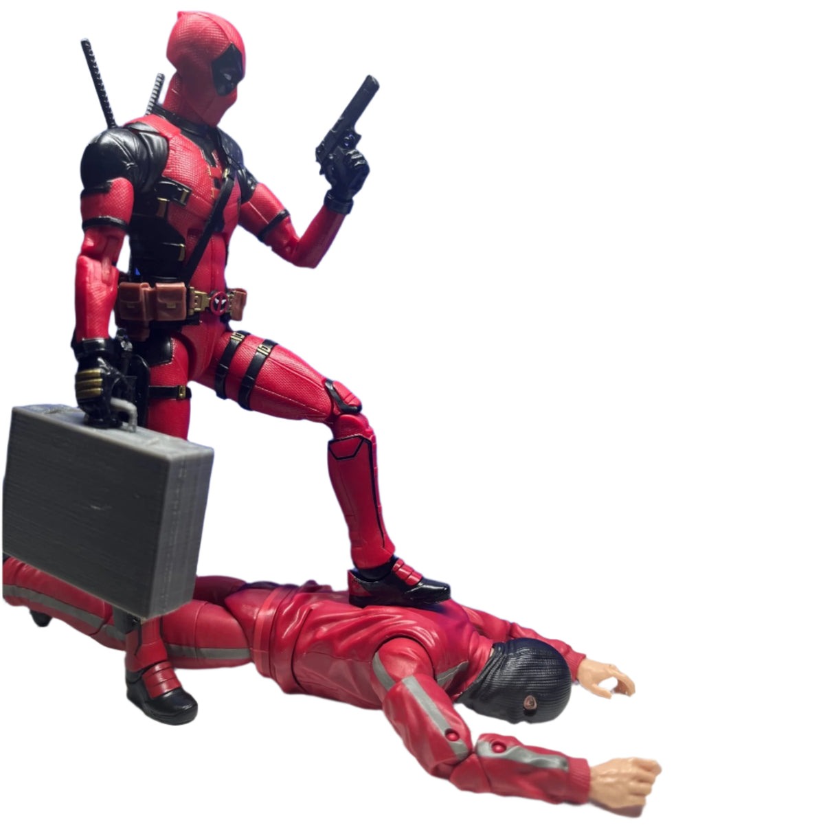 Action figure lying flat with another kneeling on one leg resting foot on back, holding miniature briefcase